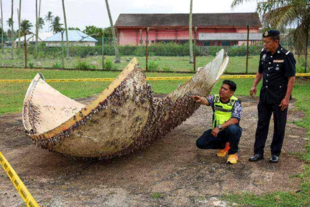 Ketua Balai Polis Nenasi, Sarjan Mejar Othman Mohamad (kanan) bersama Koperal Mohd Faizal Zainal Norddin melihat objek yang disyaki serpihan dari angkasa ditemukan di pesisir pantai Kampung Tanjung, Nenasi, Pekan pada Selasa lalu. Foto: Bernama 