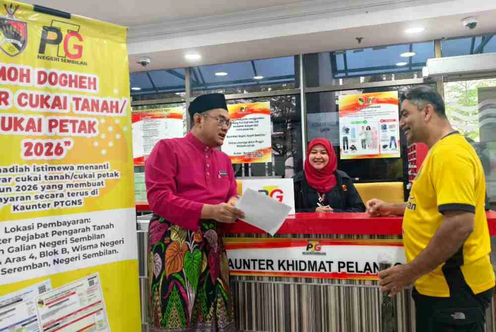 Mohd Faizal (kiri) beramah mesra dengan orang ramai yang datang ke kaunter PTGNS pada Jumaat.