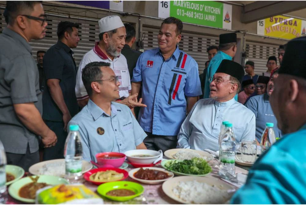Anwar (duduk dari kanan) menjamu selera sebelum menunaikan solat jumaat di Medan Selera Jalan 12, Taman Dato Harun. - Foto Bernama