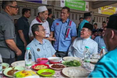 Anwar (duduk dari kanan) menjamu selera sebelum menunaikan solat jumaat di Medan Selera Jalan 12, Taman Dato Harun. - Foto Bernama