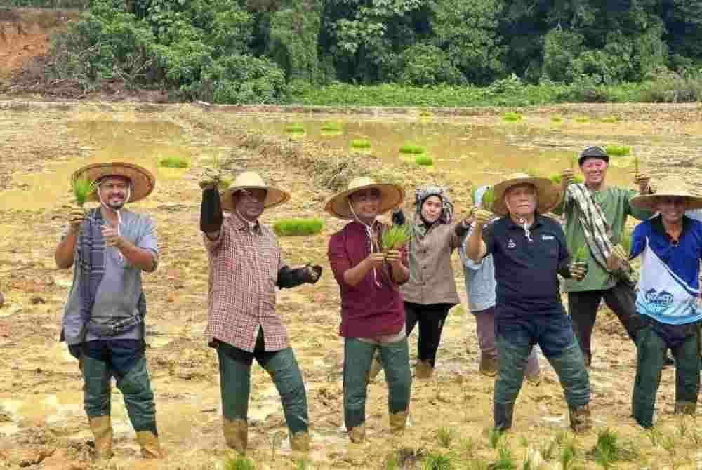 Abdul Rahman (tiga dari kiri) dan Mohd Soffi (dua dari kanan) menanam padi sebagai gimik program berkenaan.