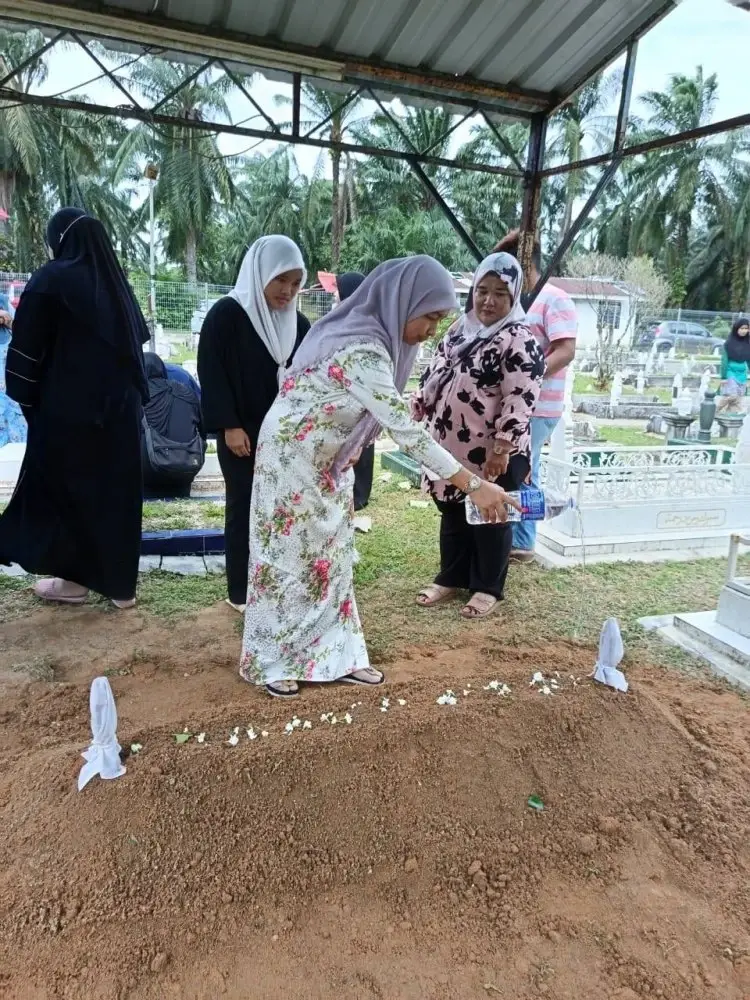 Hamizah menyiram pusara ibunya selepas pengebumian di tanah perkuburan Kampung Gemencheh Lama, di sini.