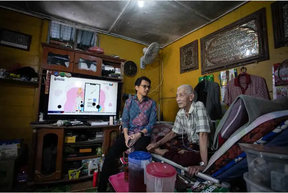 Setiausaha Politik kepada Menteri Kewangan, Muhammad Kamil Abdul Munim (kiri) bertanya sesuatu kepada Mohd Sapiee Kamarudin, 74 (kanan) ketika hadir pada sesi Ziarah Kasih MADANI di Kg Batu 17 di sini. - Foto Bernama