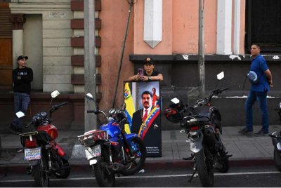 Seorang penyokong Maduro memegang potret Presiden Venezuela itu semasa satu perhimpunan berhampiran Istana Miraflores di Caracas pada 3 Januari 2026, selepas AS menawan pemimpin Venezuela. - AFP