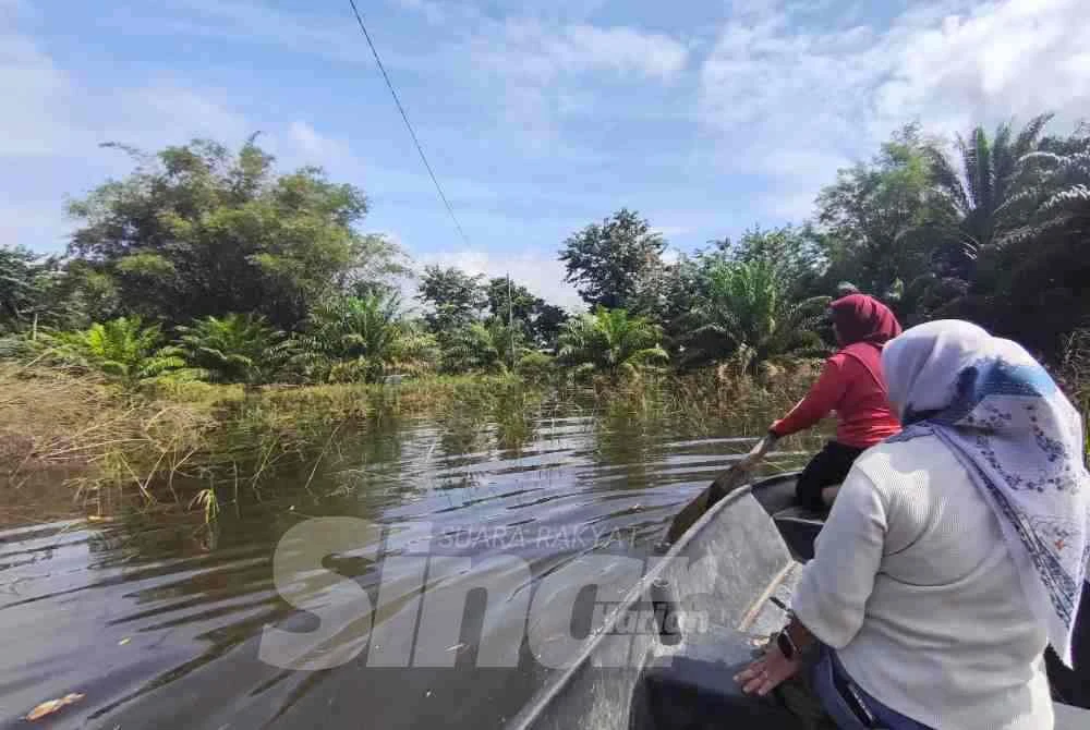 Nor Ain Aliya (depan) mendayung bot untuk ke gerai neneknya yang berada di jalan utama Kampung Temai Tengah, Pekan pada Rabu.