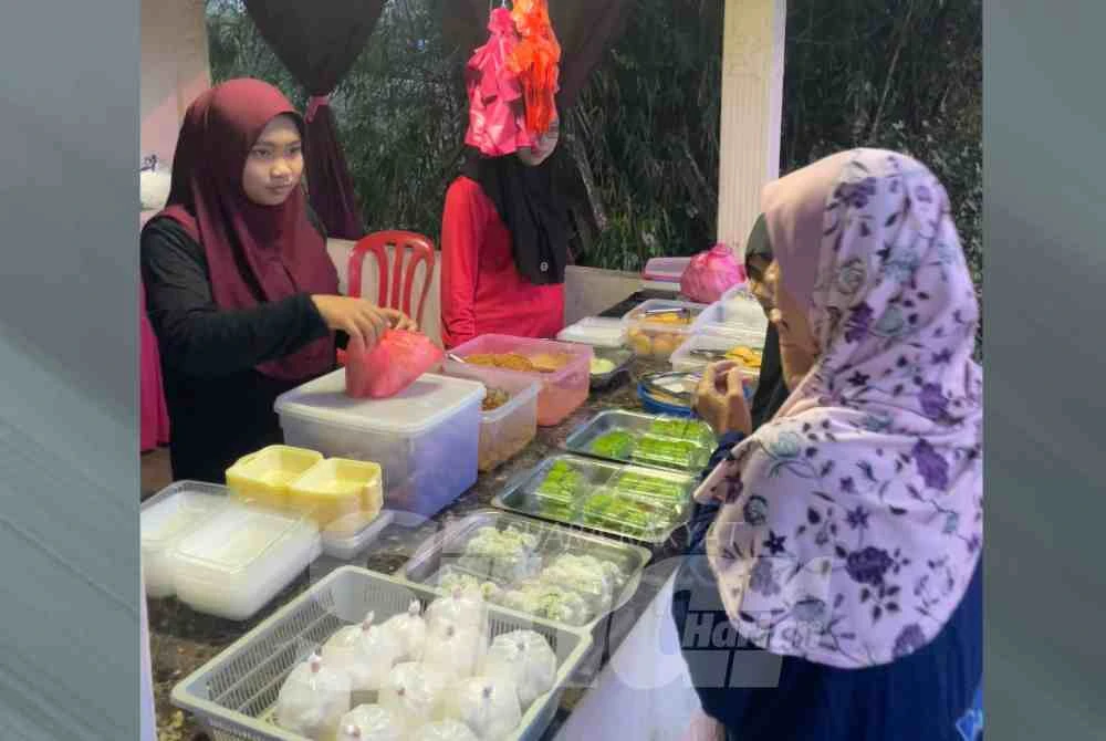 Nor Ain Aliya (kiri) membantu neneknya berniaga di gerai.