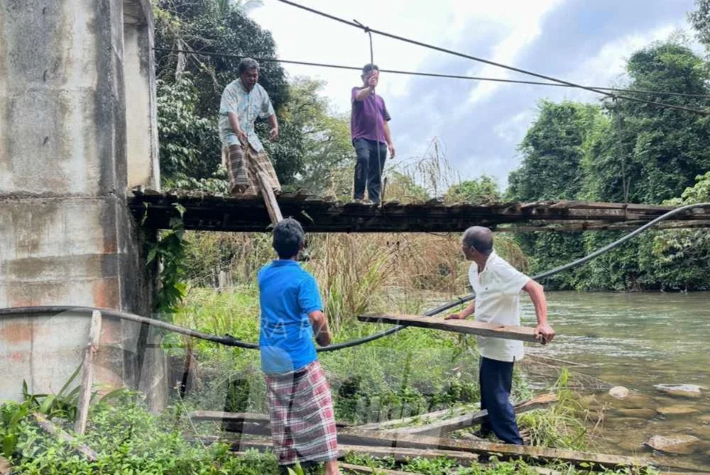 Penduduk bergotong-royong membaiki sementara jambatan selepas runtuhan. 