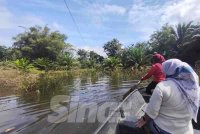 Nor Ain Aliya (depan) mendayung bot untuk ke gerai neneknya yang berada di jalan utama Kampung Temai Tengah, Pekan pada Rabu.