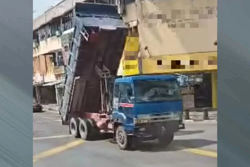 Tangkap layar video tular memaparkan timbau lori pasir tidak diturunkan sebelum merempuh lampu isyarat dan kabel elektrik di Pekan Nenas, Pontian pada Isnin.
