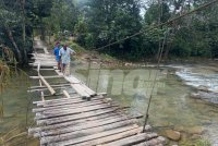 Penduduk melalui titi untuk menyeberangi sungai dari rumah mereka. Foto:ADILA SHARINNI WAHID