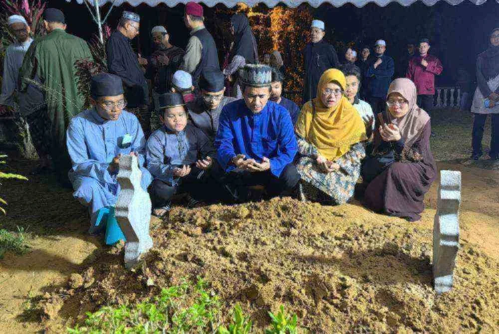 Mazli (tengah) bersama isteri dan enam anaknya di pusara Allahyarhamah Syakirah Hanan selepas selesai pengebumian di Tanah Perkuburan Islam Kubur Besar Kuala Bedah, di Kuala Terengganu sekitar jam 12.30 tengah malam pada Isnin.