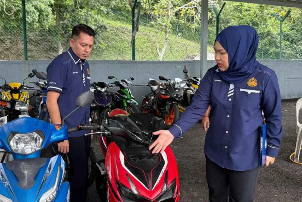 Zarina (kanan) menunjukkan motosikal yang disita menerusi operasi dijalankan pada Rabu.