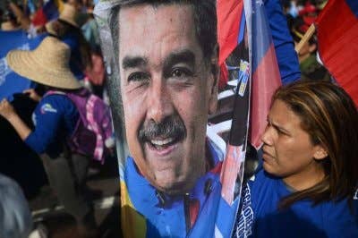 Seorang penyokong memegang gambar Presiden Venezuela yang digulingkan, Nicolas Maduro, semasa perhimpunan menyokong beliau dan isterinya, Cilia Flores, di Caracas. - AFP