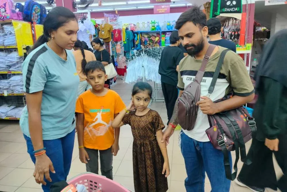 Kalaiarasan (kanan) bersama isteri memilih kelengkapan persekolahan anak-anak mereka di Pasaraya Borong Sakan Klebang pada Rabu.