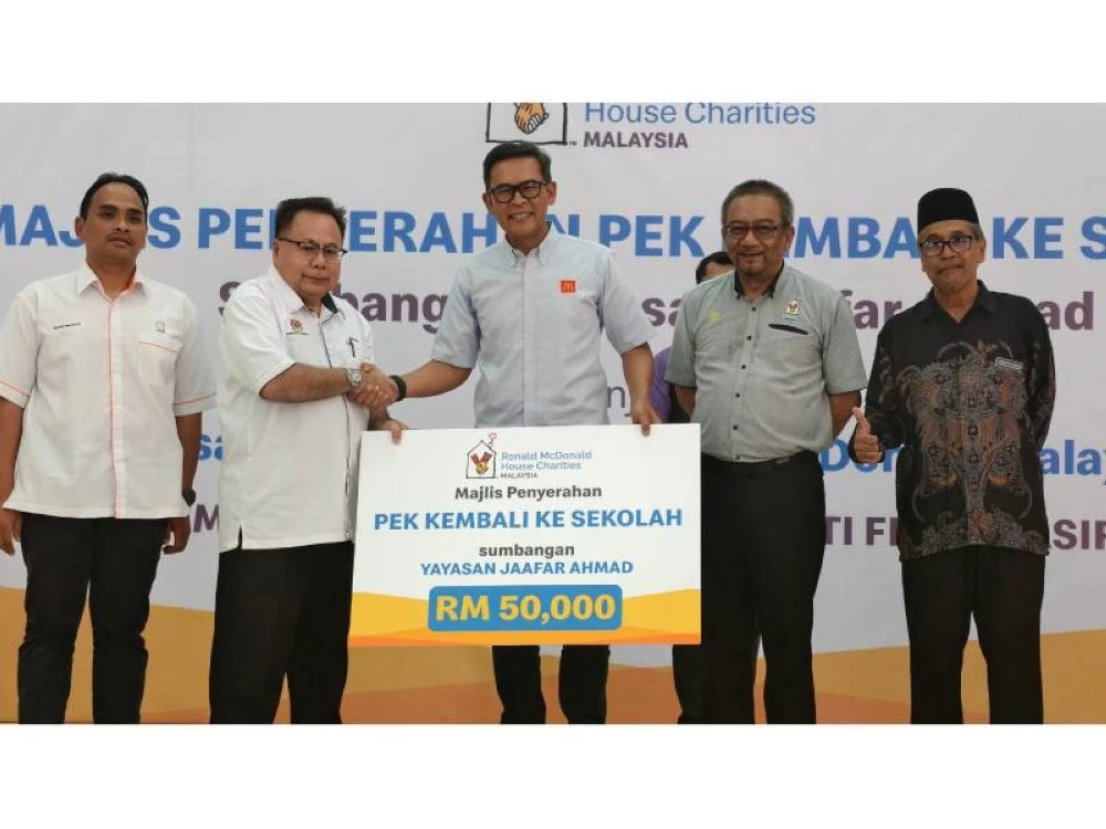 Azmir menyerahkan sumbangan Pek Kembali Ke Sekolah kepada wakil Pejabat Pendidikan Daerah Tampin.