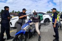 Mohammad Yusoff memeriksa lesen memandu seorang penunggang motosikal dalam Operasi Pengarah di hadapan SK Tasek di Jalan Sultan Azlan Shah, Ipoh pada Khamis.