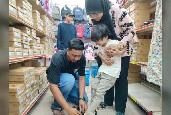 Mior Mohd Asri memilih kasut sekolah untuk anaknya sempena Program Kembali Ke Sekolah Tahun 2026 di bawah Inisiatif Sejahtera Madani di sebuah pasar raya di Klebang pada Rabu.