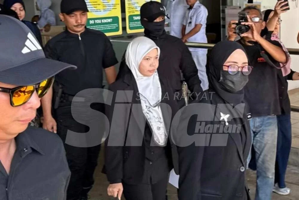 Surita (tengah) hadir ke HTJ bersama jurubahasa dan polis untuk prosiding pertuduhan terhadap 'Ayang' pada Jumaat.