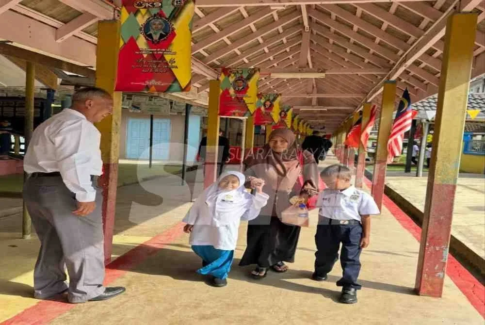 Siti Nur Najwa (kiri) dan adiknya berjalan bersama ibu mereka pada hari pertama persekolahan.