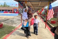 Siti Nur Najwa (kiri) didukung ibunya untuk ke kelas.
