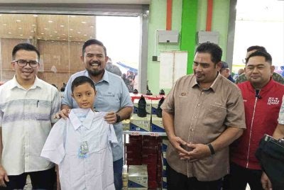 Manndzri (dua dari kiri) membantu seorang murid mencuba uniform sekolah sewaktu program Back To School Parlimen Tenggara.