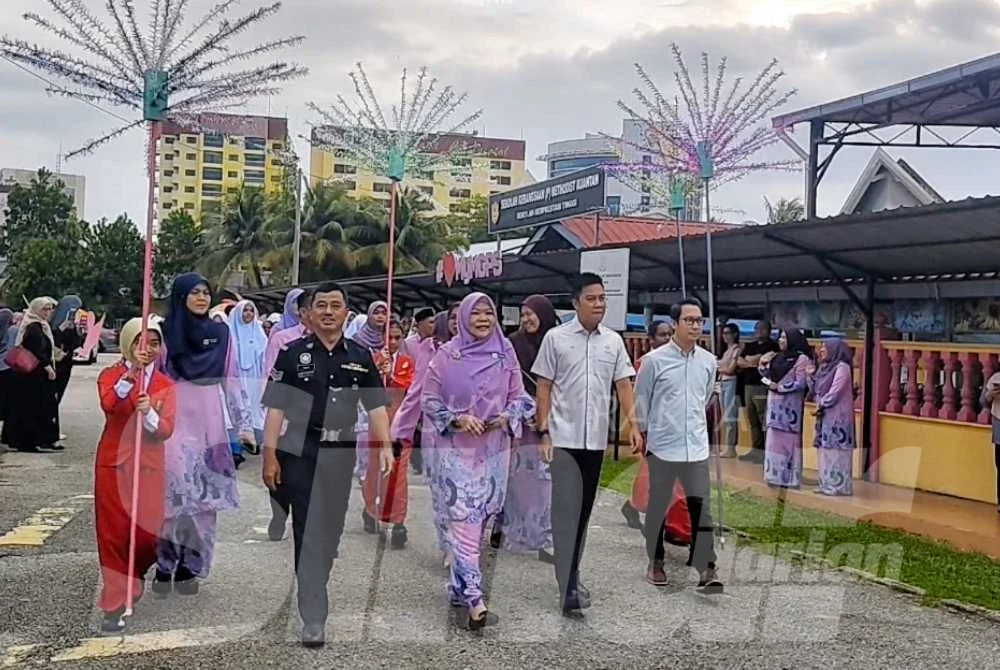 Masniza (tengah) dan Khairul Anwar (kanan) berjalan mengiringi 54 bekas murid MGPS ke Tingkatan Satu di MGSS pada Program Mengirim Kasih