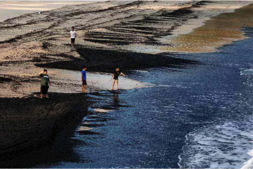 Pantai Teluk Kalong dekat sini dicemari bahan pepejal berwarna hitam, dipercayai arang batu yang terdampar di sepanjang pesisir sejak dua hari lalu. - Foto: Bernama