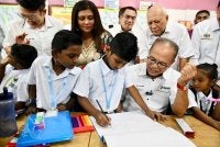 Wan Rosdy meluangkan masa beramah mesra sambil memerhatikan salah seorang murid melukis menggunakan alat tulis dari kit Program Tunas Makmur yang beliau sampaikan. FOTO FB WAN ROSDY WAN ISMAIL