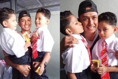 Mohd Azwan mendukung Akif (kanan) dan Afif (kiri) pada hari pertama sekolah di SK Dato' Onn Jaafar, Simpang Renggam, Kluang.