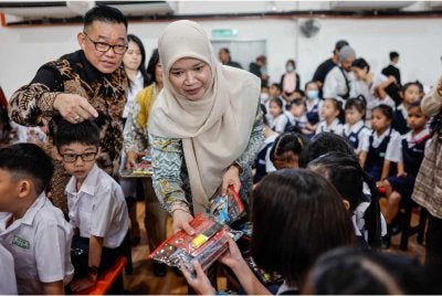 Fadhlina menyampaikan set alat tulis kepada murid pada Majlis Perasmian SJKC Ladang Regent Elmina hari ini - Foto: Bernama