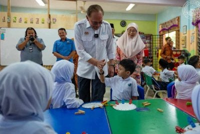 Anwar bersama isteri, Wan Azizah menyantuni murid-murid di hari pertama sesi persekolahan. Foto Pejabat Perdana Menteri