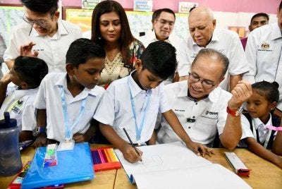 Wan Rosdy meluangkan masa beramah mesra sambil memerhatikan salah seorang murid melukis menggunakan alat tulis dari kit Program Tunas Makmur yang beliau sampaikan. FOTO FB WAN ROSDY WAN ISMAIL