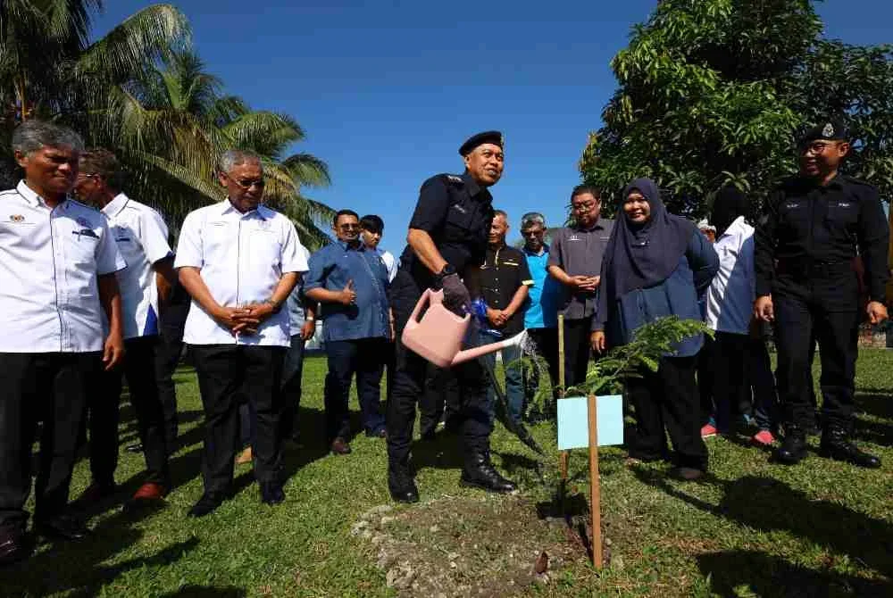 Mohamad Nasir menyiram pokok celagi (asam jawa) sebagai gimik perasmian program 'High Profile Policing' (HPP) di Balai Polis Pokok Assam, Taiping pada Selasa.