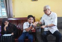 Ismail Sabri (kanan) menyantuni anak yatim ketika menyerahkan bantuan persekolahan sebanyak RM300.