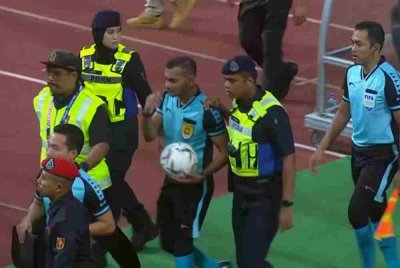 Logeswaran (tengah) diiringi keluar padang dengan kawalan ketat anggota keselamatan dan polis selepas tamat perlawanan.