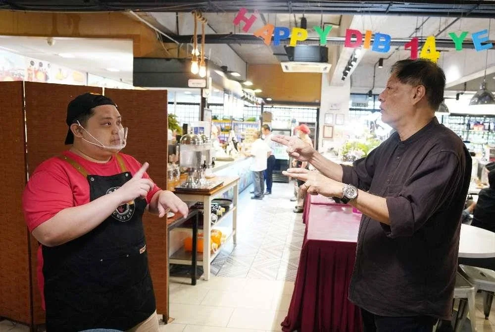 Allen berkomunikasi dengan salah seorang pekerja menggunakan bahasa isyarat, pendekatan yang menjadi asas operasi DIB sejak ditubuhkan pada 2011.