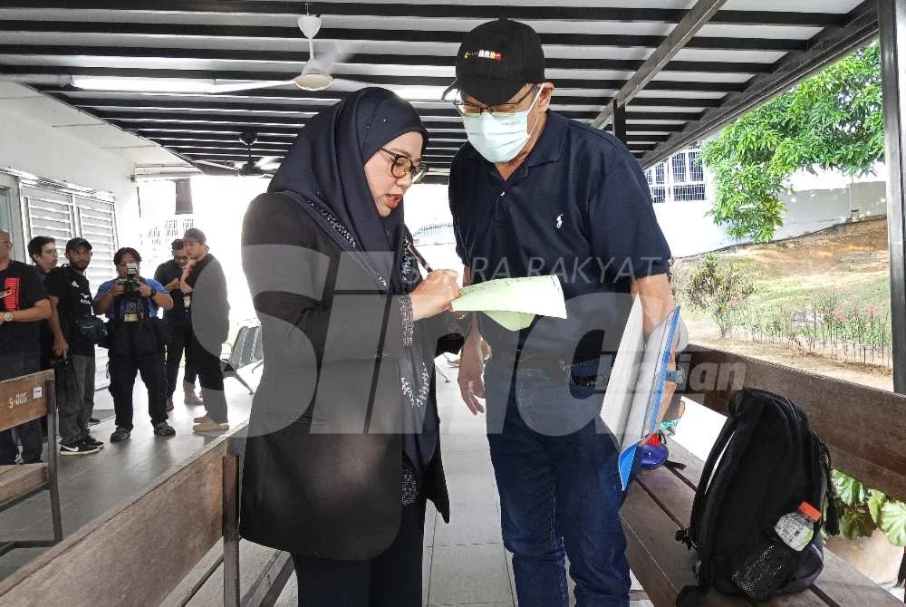 Sa Kaw (kanan) berbincang dengan peguam sebelum pertuduhan dilakukan di Mahkamah Majistret Kulai pada Rabu.