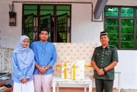 Rosyamimie Syahira (kiri) dan suaminya, Muhammad Shah Amirul menerima tiga hadiah kurniaan Al-Sultan Abdullah dan Tunku Azizah yang sampai wakil istana,Anuar (kiri) di kediaman mereka di Kampung Paya Pulai pada Selasa. Foto FB Kesultanan Pahang.