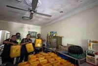 Jegan (kanan) bersama pegawai KPDN Pulau Pinang menunjukkan minyak paket yang dirampas di sebuah stor di Butterworth, pada Rabu.