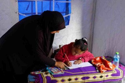 Yasmine al-Ajouri membantu anaknya menyiapkan kerja rumah yang diberikan guru.