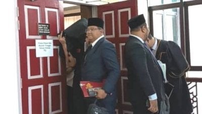Tertuduh (kiri) ketika dihadapkan di Mahkamah Tinggi Syariah Terengganu di Kuala Terengganu pada Rabu atas dakwaan berpakaian dan berlagak seperti wanita di sebuah pusat beli-belah pada Mei tahun lalu.