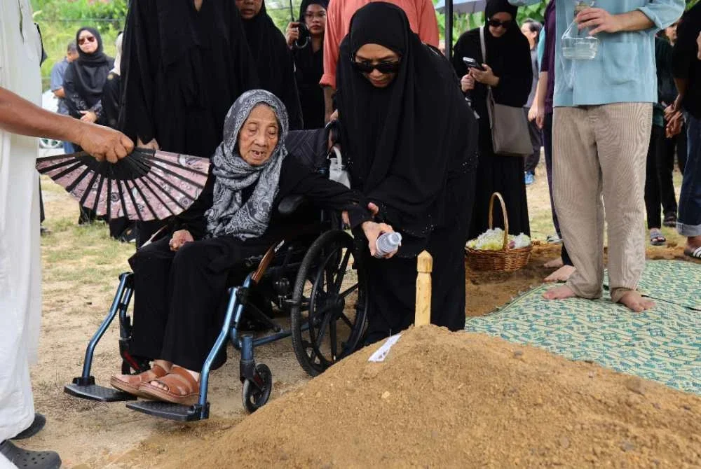 Balu Allahyarham Mohd Farid, Siti Mariam menyiram pusara suaminya di Tanah Perkuburan Bukit Buak. Foto Bernama