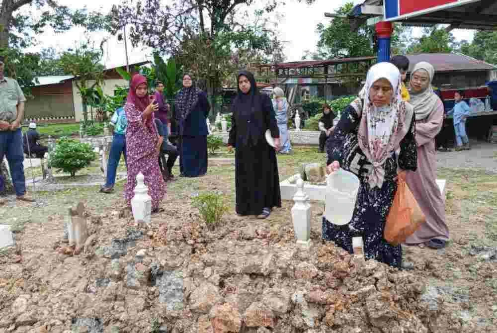 Siti Fatimah menyiram air di pusara suaminya di Tanah Perkuburan Islam Kampung Parit Semerah, Pontian.