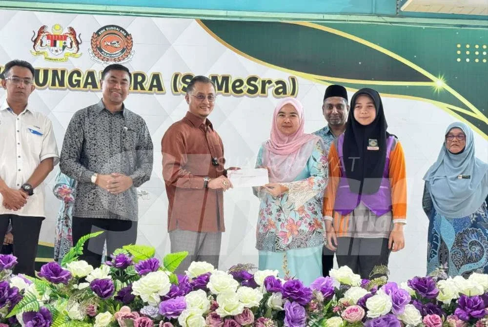 Mohamad (tiga dari kiri) menyampaikan wang BAP 2026 di SMK Sungai Ara pada Khamis.