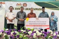 Mohamad (tengah) menyampaikan cek cura bernilai RM4.33 juta bagi BAP 2026 daerah Barat Daya di SMK Sungai Ara pada Khamis.