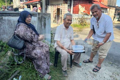 Syed Abdul Hamid (tengah) memegang al-Quran bersama air zamzam yang selamat dalam kebakaran rumahnya. - Foto Sinar Harian/Adila Sharinni Wahid
