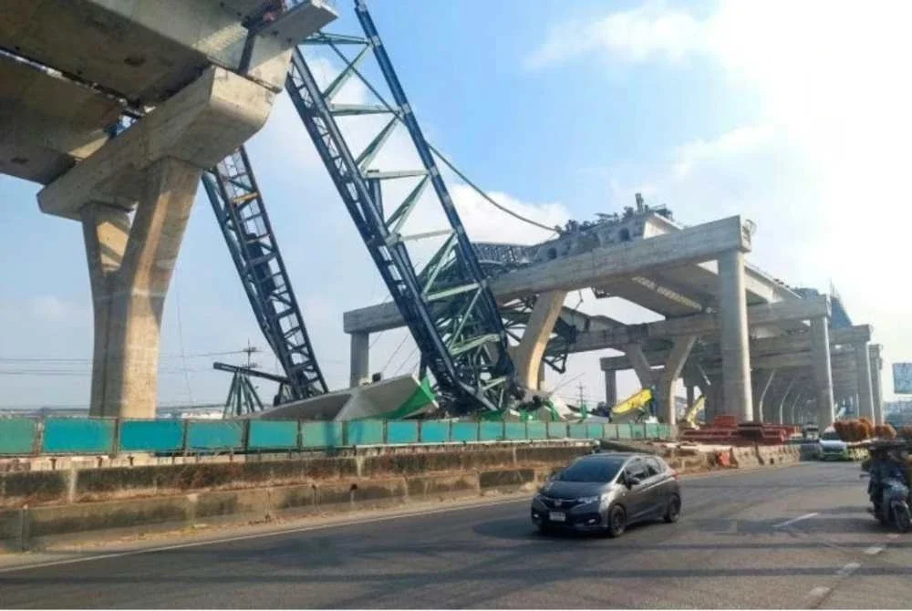 Kereta-kereta melintas di sebelah kren yang runtuh dan meranapkan dua kenderaan semasa pembinaan lebuh raya bertingkat di wilayah Samut Sakhon, Thailand. - Foto: Agensi