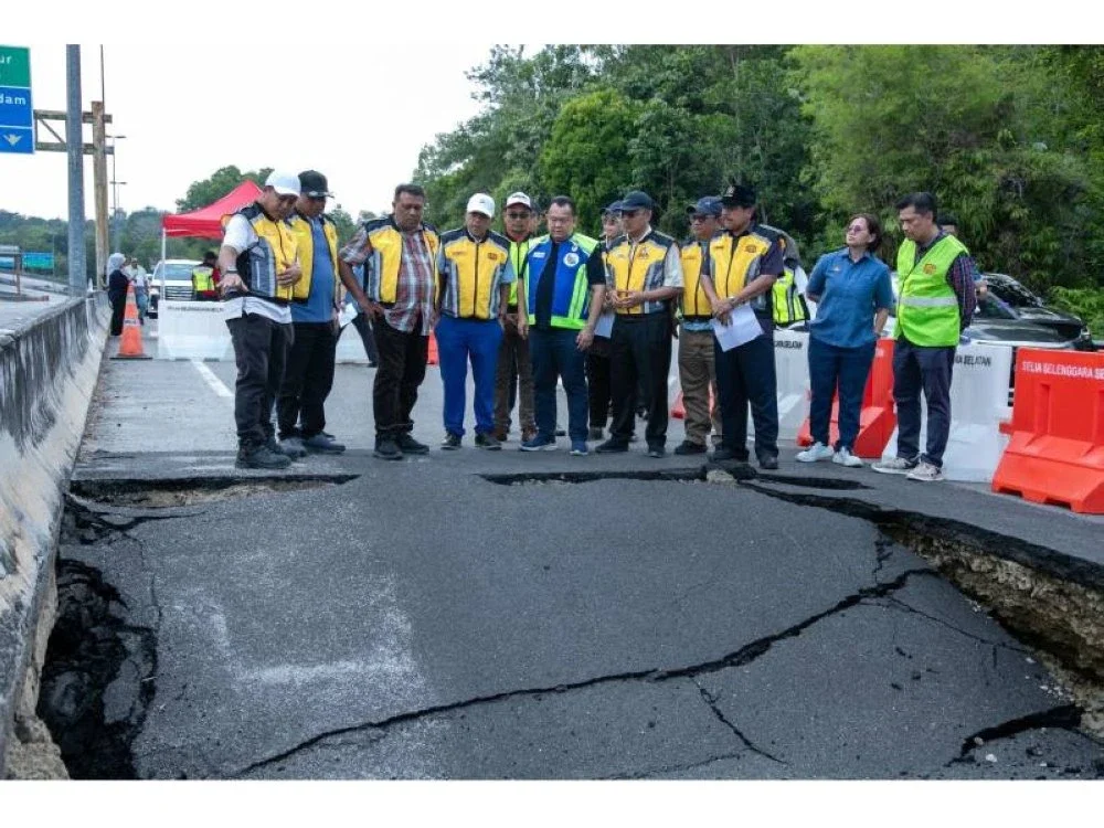 Alexander bersama pegawai KKR meninjau kerosakan jalan akibat mendapan tanah dalam lawatan tapak, sebagai sebahagian usaha mempercepat pelaksanaan kerja pembaikan dan memastikan keselamatan pengguna jalan raya.