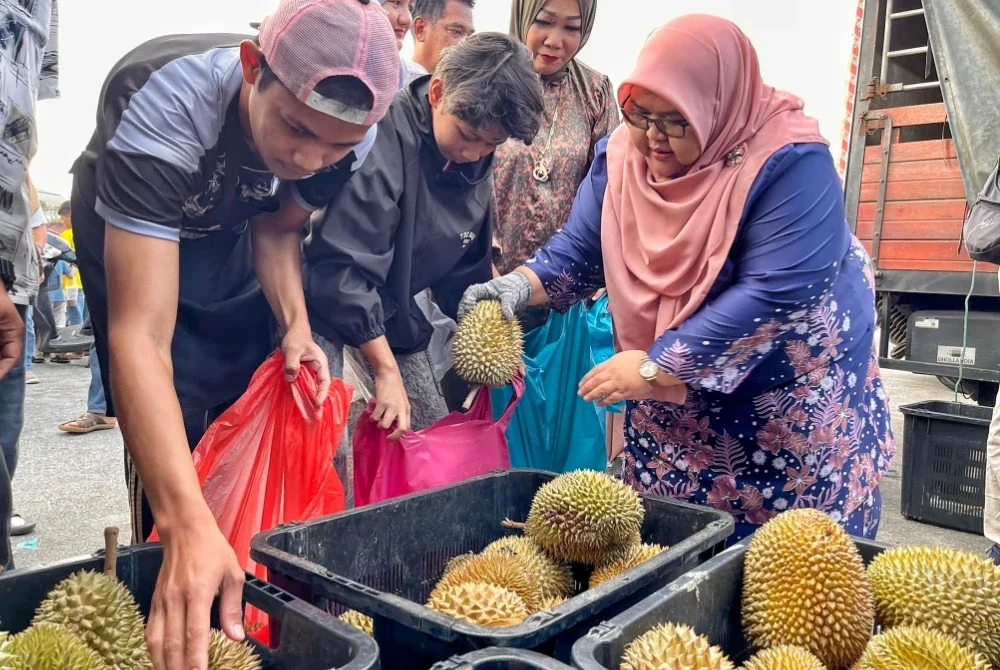 Rashiha (kanan) memilih durian untuk diberikan kepada pelanggan yang ingin membeli raja buah itu ketika program jualan di Pasar Tani Beserah pada Khamis. Foto FAMA Pahang