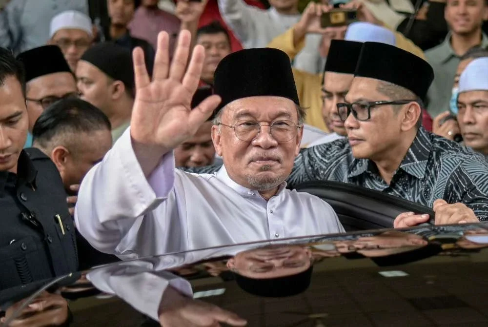 Anwar melambaikan tangan ke arah jemaah selepas menunaikan solat Jumaat di Masjid Usamah Bin Zaid pada Jumaat. Foto: Bernama 